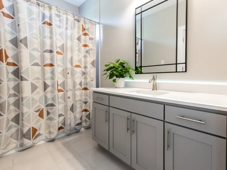 Modern bathroom with new shower curtain, painted vanity, and stylish mirror