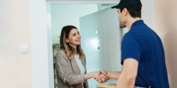young happy woman standing doorway shaking hands with delivery man while receiving package scaled 1